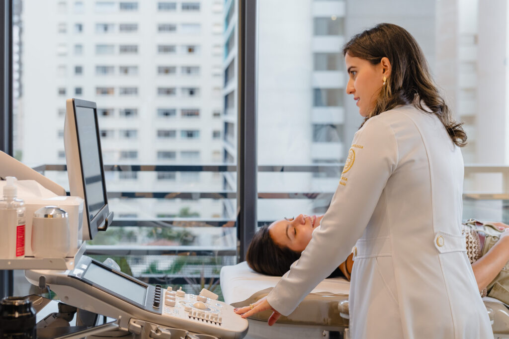 Dra. Natalia realizando ultrassom de tireoide em paciente deitada